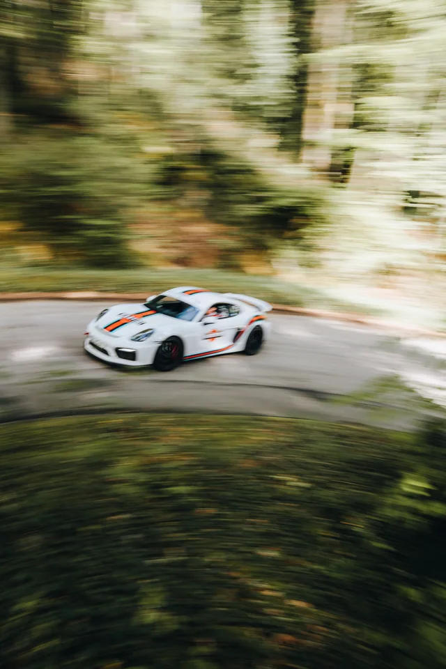 Porsche GT4 driftet durch eine Waldkurve